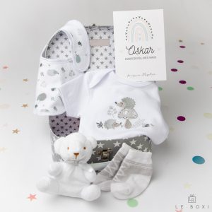 Darilo za novorojenčka in mamico. Siv darilni kovček z belimi zvezdicami vsebuje bombažni siv komplet z motivom ježka z bodijem, slinčkom in nogavičkami iz mehkega bombaža ter plišastim medvedkom