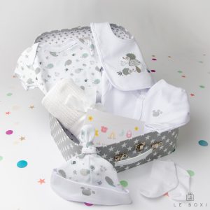Siv darilni kovček z belimi zvezdicami vsebuje bombažni sivi komplet z motivom ježka z bodijem, slinčkom in nogavičkami iz mehkega bombaža, plišastim medvedkom ter mehko bombažno pleteno odejico